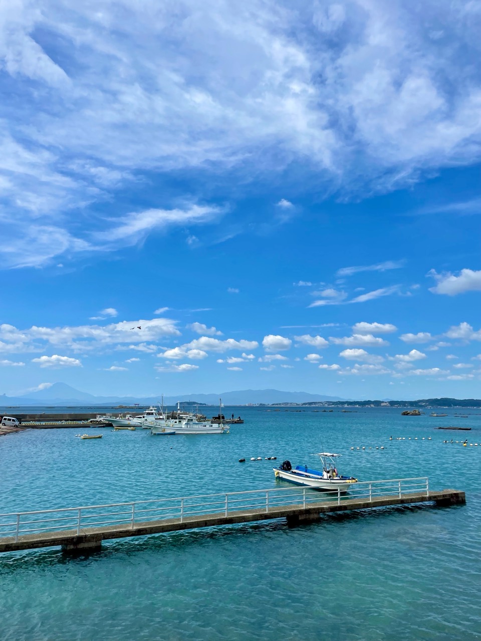 青空と雲の下、港に浮かぶ小さな船。