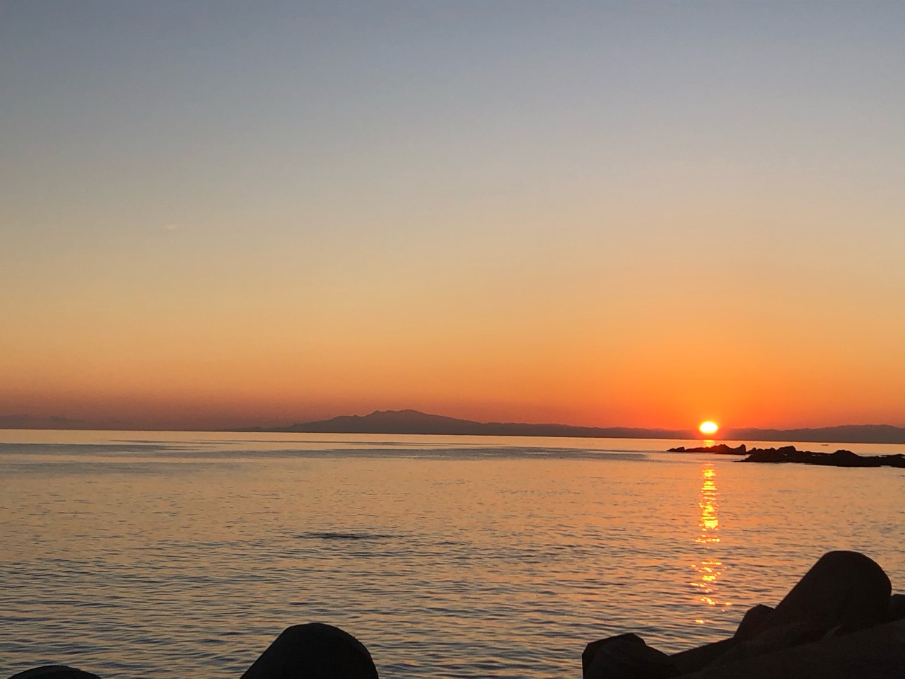 海に沈む夕日と、水面に伸びる金色の光。