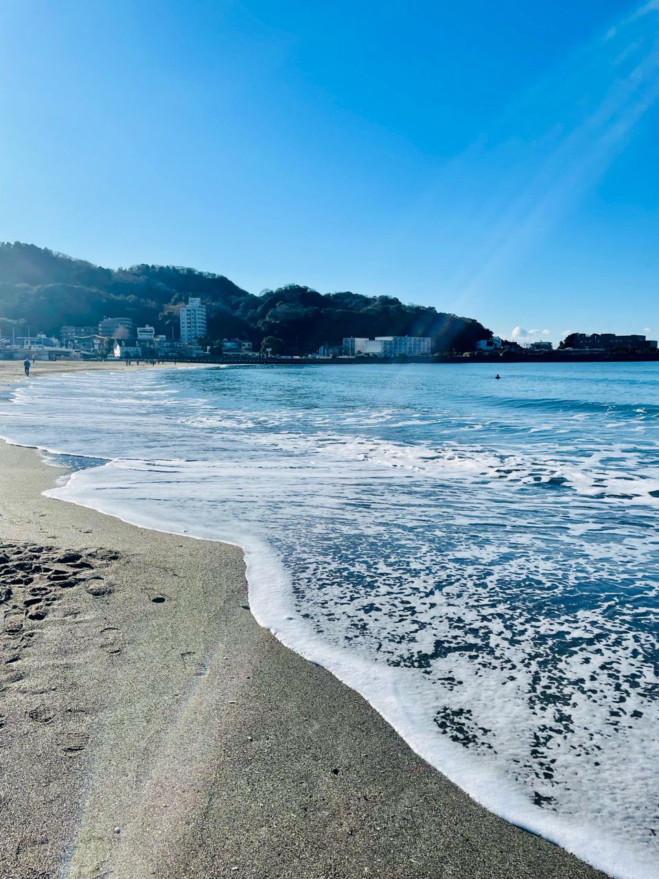 砂浜に沿ってゆるやかにカーブする白い波。